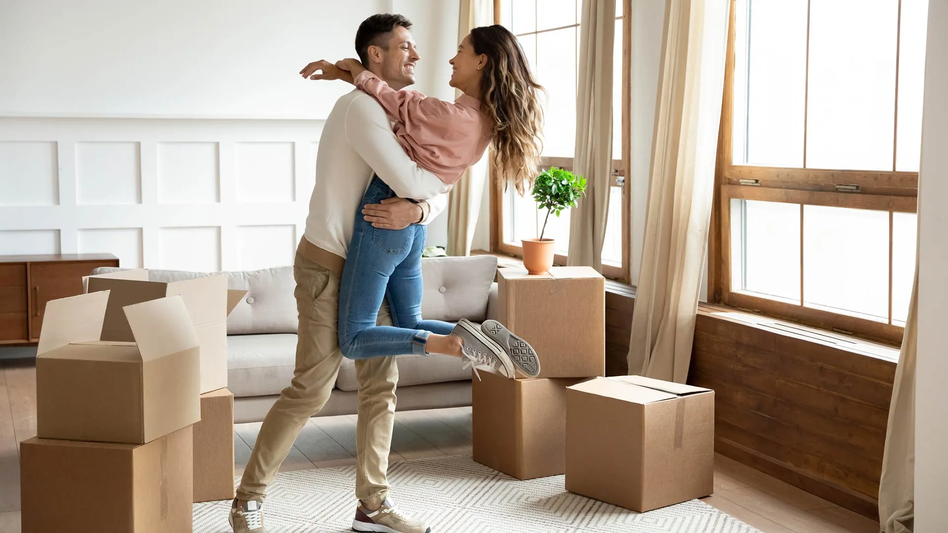 A couple sharing a celebratory embrace while unpacking in their new home.